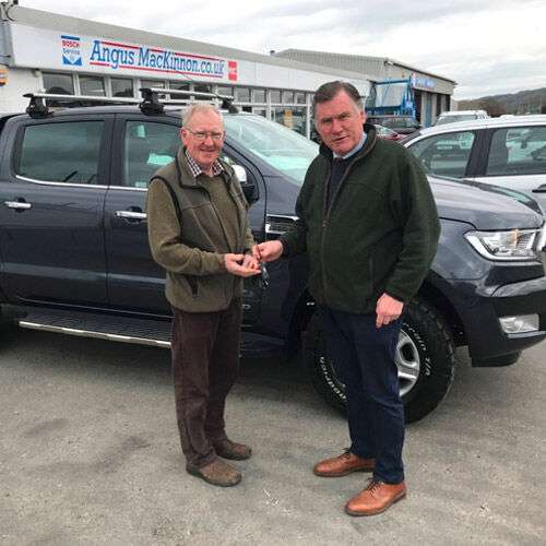 Angus MacKinnon (right) shaking hands with a customer.
